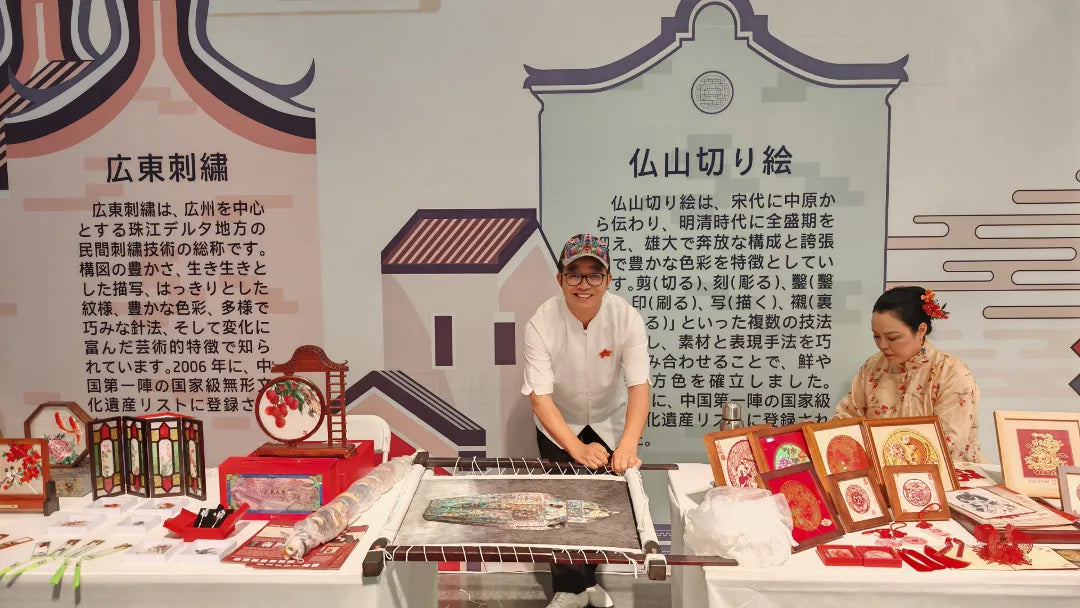 Cantonese embroidery master Wang Xinyuan demonstrating his craft at the Tokyo World Tour, showcasing heritage threads and Eastern colors.