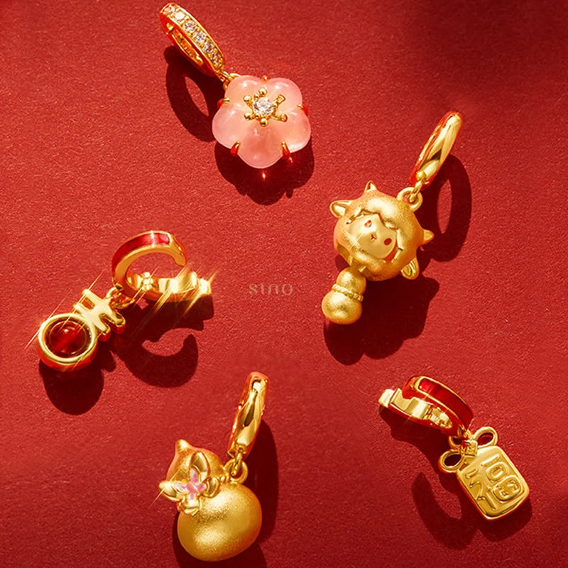 Close-up of five gold-tone charms for the 2027 Year of the Goat red agate bracelet, featuring a pink blossom, a goat-inspired pendant, a red agate charm and auspicious Chinese symbols, perfect for Chinese New Year gifting.