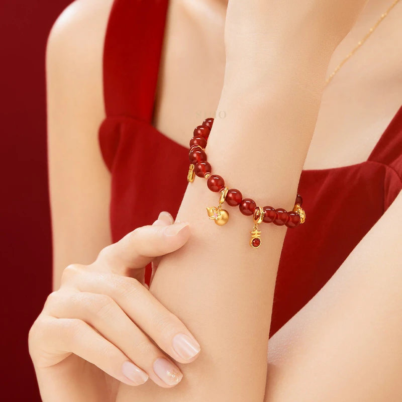 Red agate beaded bracelet with gold-tone lucky charms worn on the wrist, a festive Chinese New Year jewelry accessory and thoughtful Year of the Goat gift for her.