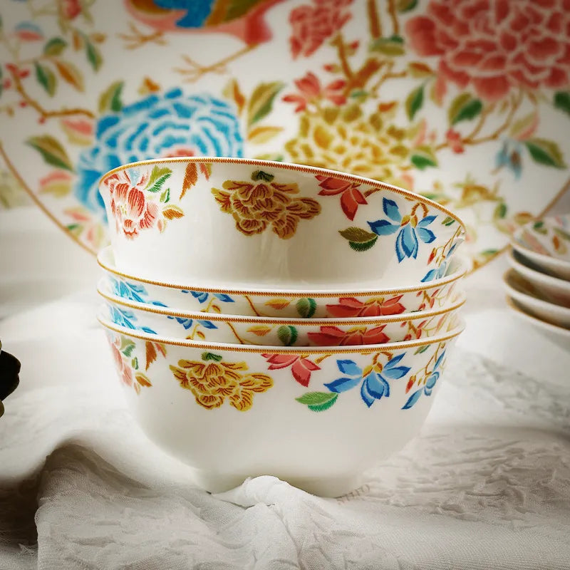 Four Chinoiserie bowls stacked with floral plate in background.
