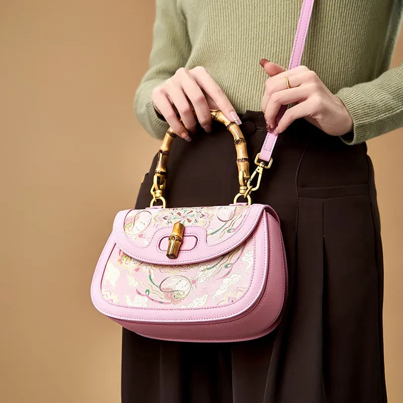 Model wearing the pink Song brocade handbag as a crossbody, highlighting its adjustable strap and bamboo handle.