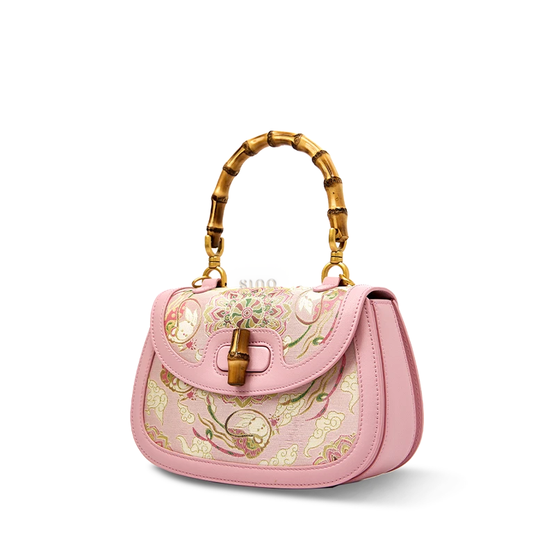 Side view of the pink Song brocade handbag, showcasing its structured silhouette and bamboo handle.
