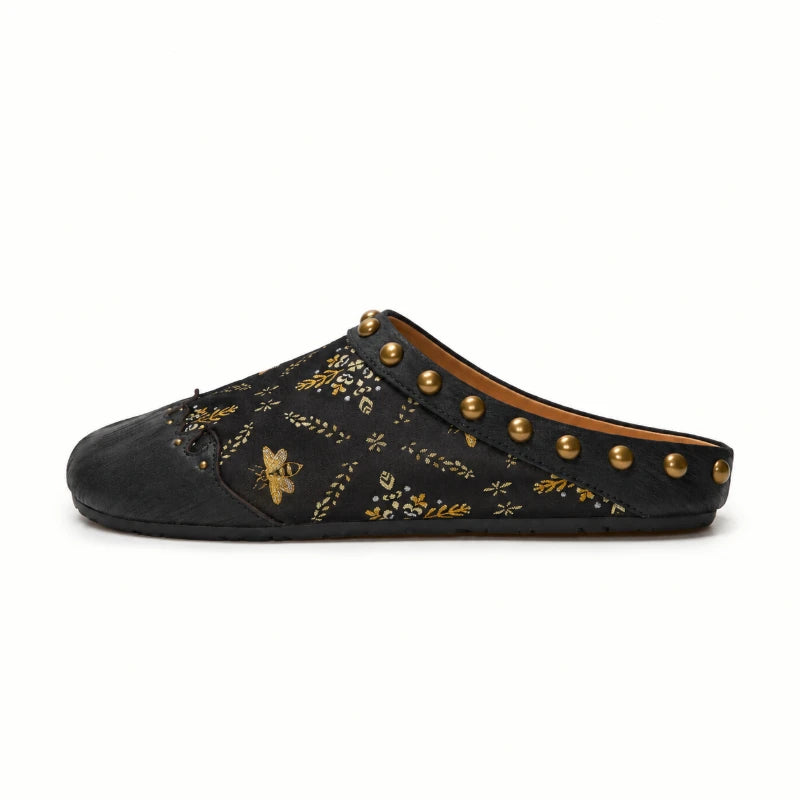 Side view of black Shu Brocade mules showing the rounded closed toe, open-back slip-on style, gold stud accents, and refined Chinese silk craftsmanship.