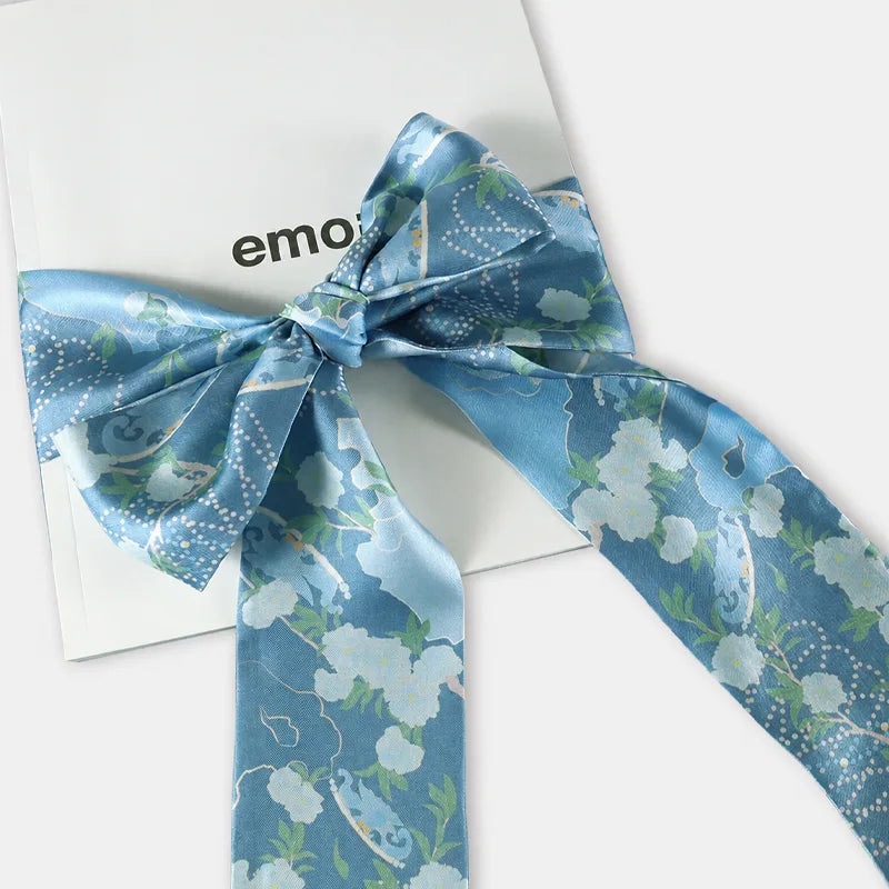Chinese Blooming Peony Mulberry Silk Twilly tied into an elegant bow, highlighting the blue floral print and smooth silk sheen.