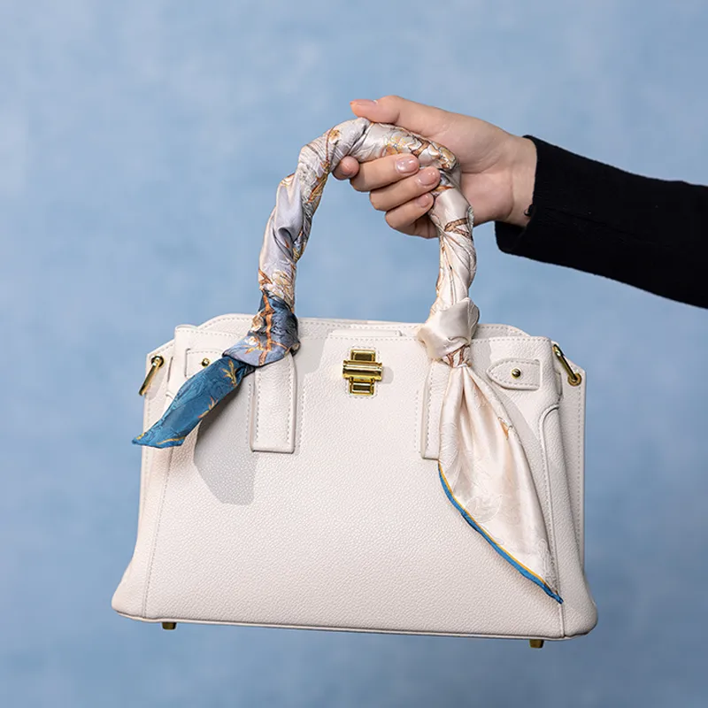 Blue side of the Nanjing Brocade Bloom mulberry silk square scarf wrapped around a white handbag handle.