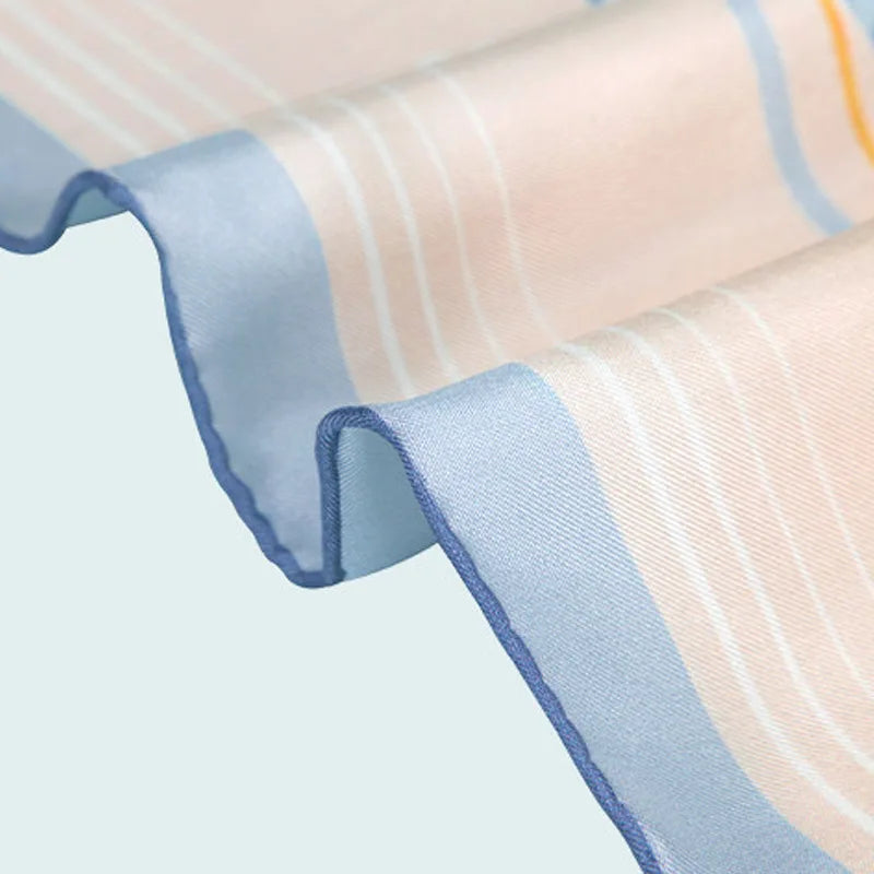 Close-up of the hand-rolled blue edge on the Butterfly Dream Mulberry Silk Square Scarf with fine silk twill texture.
