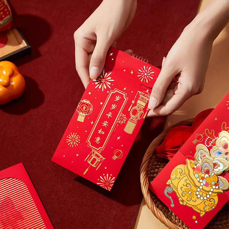 Red Chinese New Year hongbao held in hand, decorated with gold Chinese blessing text, traditional lantern illustrations, and festive firework motifs.