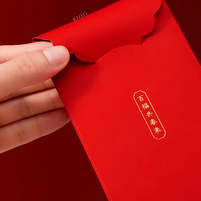 Close-up of a traditional Chinese red money envelope showing its scalloped closure flap and gold Chinese blessing characters on a bright red surface.