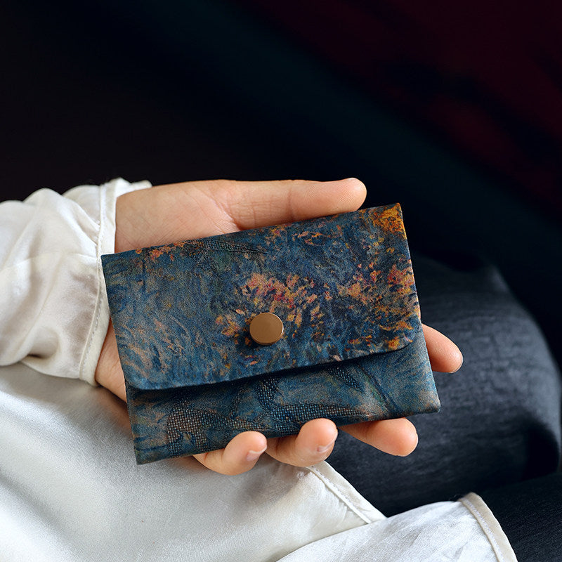 Handheld lifestyle view of the Chinese Xiangyunsha Silk Deep Blue Spring Bloom Snap Card Holder Wallet, highlighting its compact shape and artistic floral textile design.