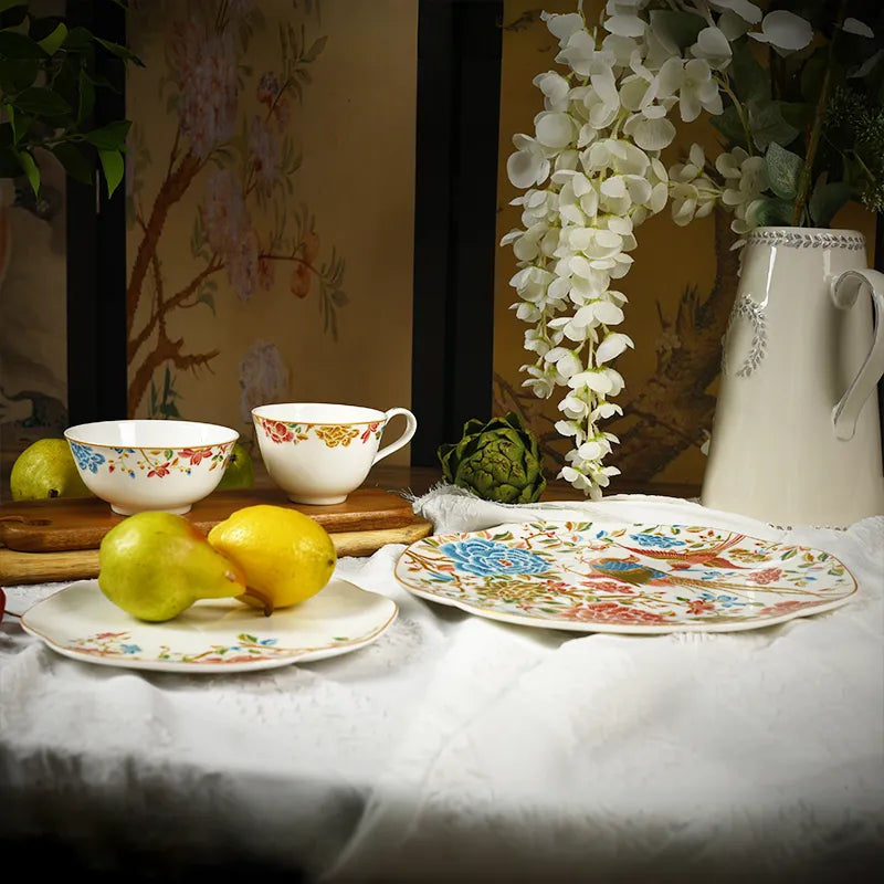 Front view of 4-piece Chinoiserie bone china set: square plates, bowl, teacup with floral & bird design.