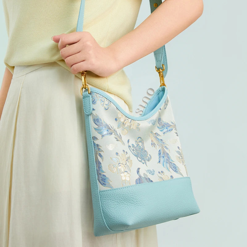 Side view of a model carrying the Chinoiserie Golden Jade Romance leather shoulder bag with an adjustable strap.