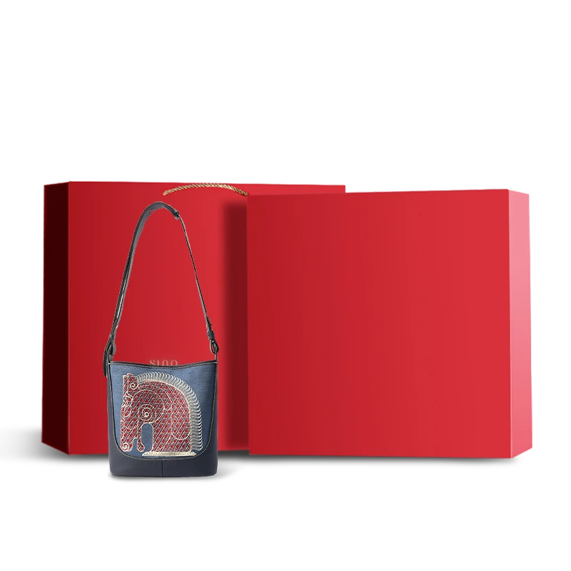 Red luxury gift box with gold branding, containing embroidered leather crossbody bag.