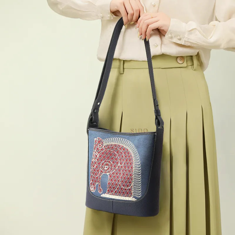 Asian woman wearing crossbody bag diagonally, horse embroidery detail visibleoverlay.