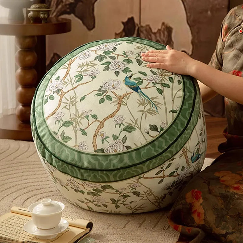 Model gently lifting the chinoiserie jade green couch cushion pouf, highlighting the floral and bird pattern.