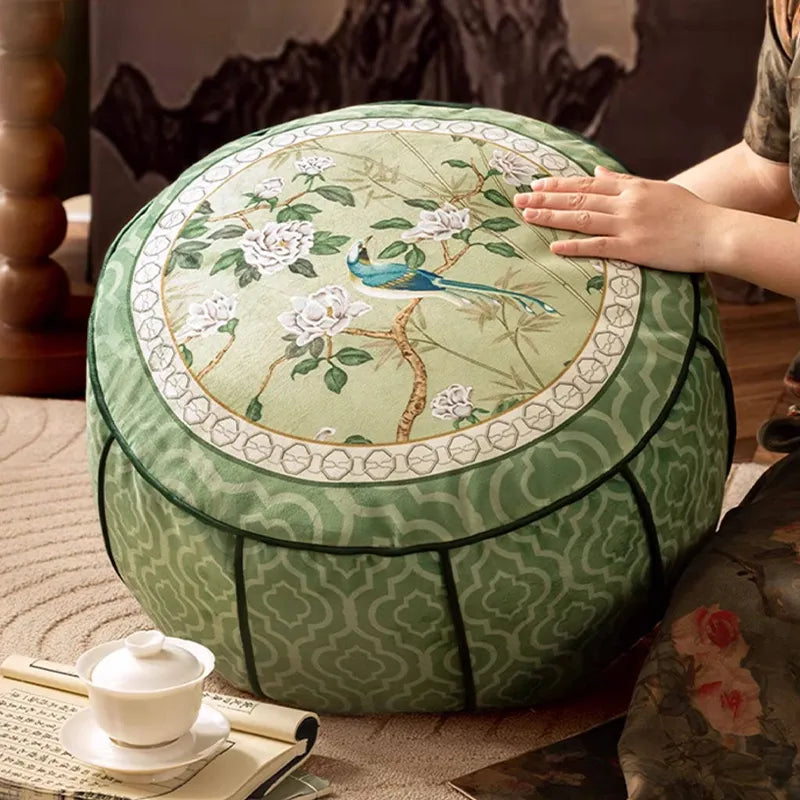Model gently lifting the chinoiserie jade green rest floor pouf, highlighting the floral and bird pattern.