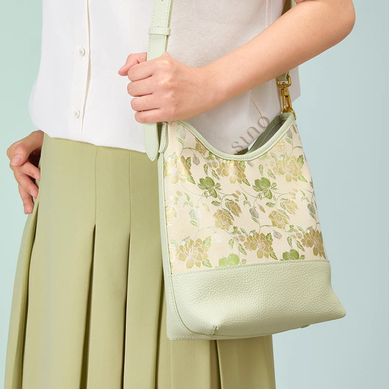 Model wearing the Chinoiserie Jasmine Green Plum Song Brocade shoulder bag with an adjustable leather strap.