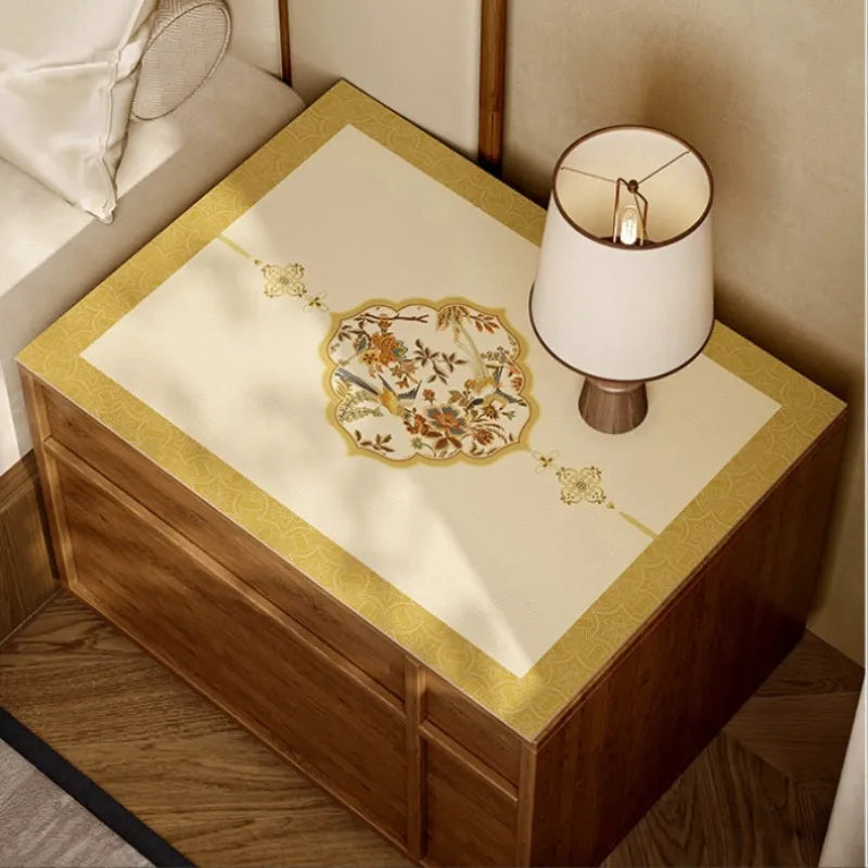 Ivory and golden Autumn Splendor leather nightstand mat with central Chinoiserie floral and bird medallion.