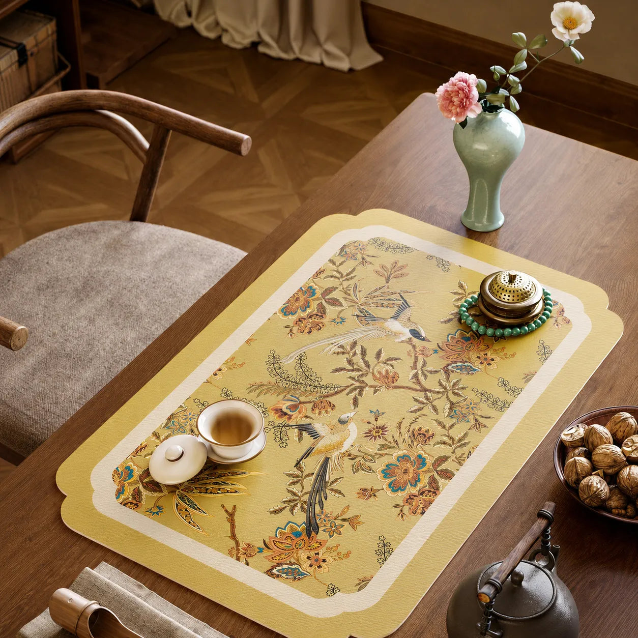 Autumn Splendor leather tea table mat featuring golden floral and bird motifs with teacup and incense burner on a wooden tea table.