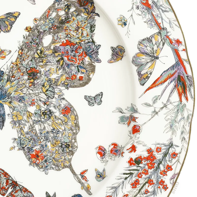 Close-up: Right butterfly wing and hand-painted flowers on plate edge.