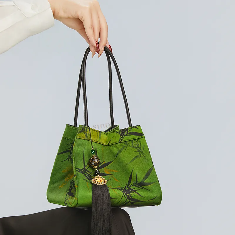 Model seated with the dark green bucket bag placed on the knees.