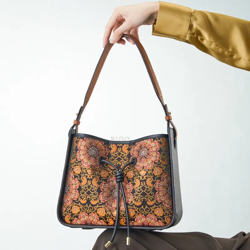 Elegant seated display of Chinoiserie brocade bag on lap.