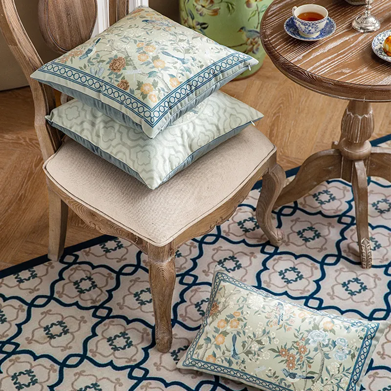 Stacked chinoiserie pillows on chair with one on floor.