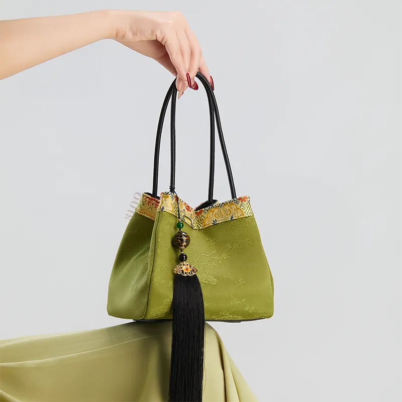 Model seated with the light green bucket handbag placed on the knees.