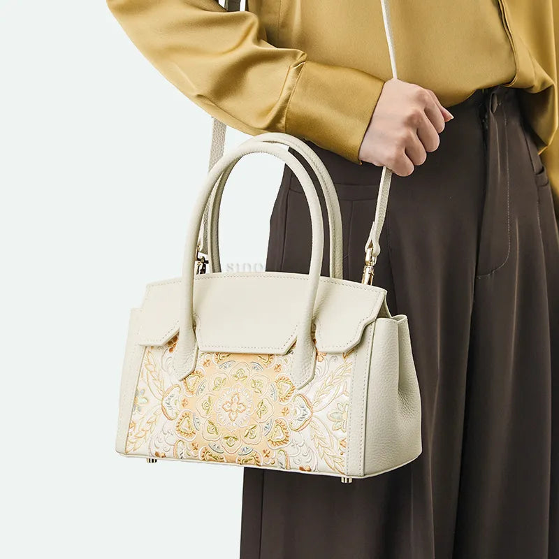 Model shoulder-carrying chinoiserie lotus motif leather handbag.