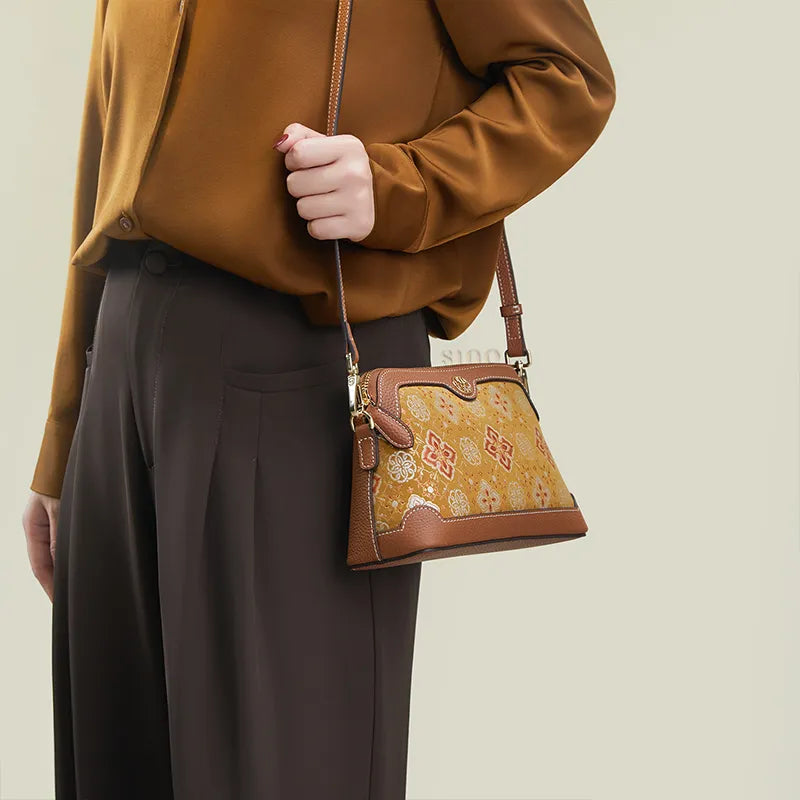 Model standing sideways wearing the Persimmon Calyx Motif clutch bag as a shoulder bag.