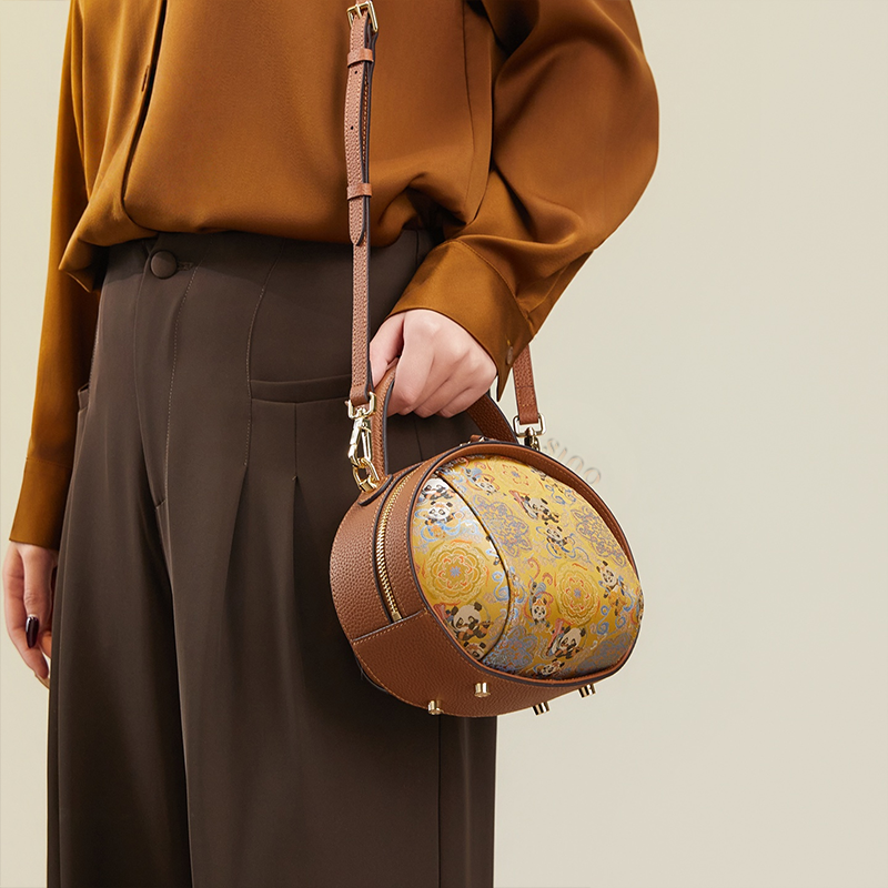 Model standing right with brown Song Brocade handbag (Panda Pattern) over one shoulder.