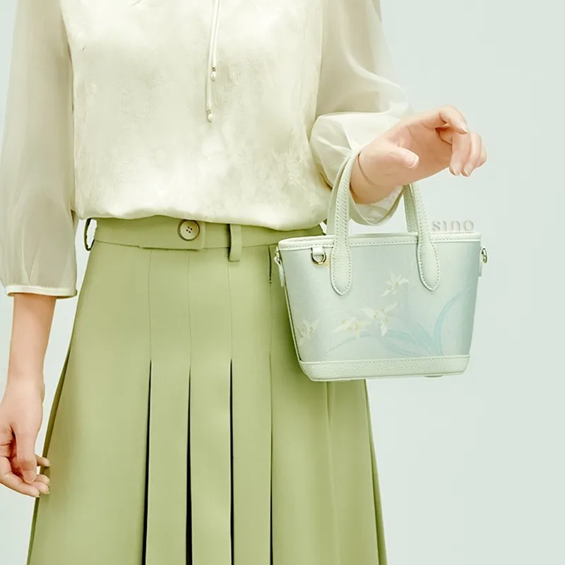 Model standing front-facing with Chinoiserie Luxury Song Brocade Orchid Handbag over one shoulder.