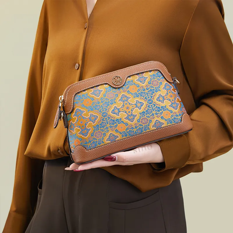 Model standing sideways holding the Ruyi Motif clutch bag with one hand angled downward.