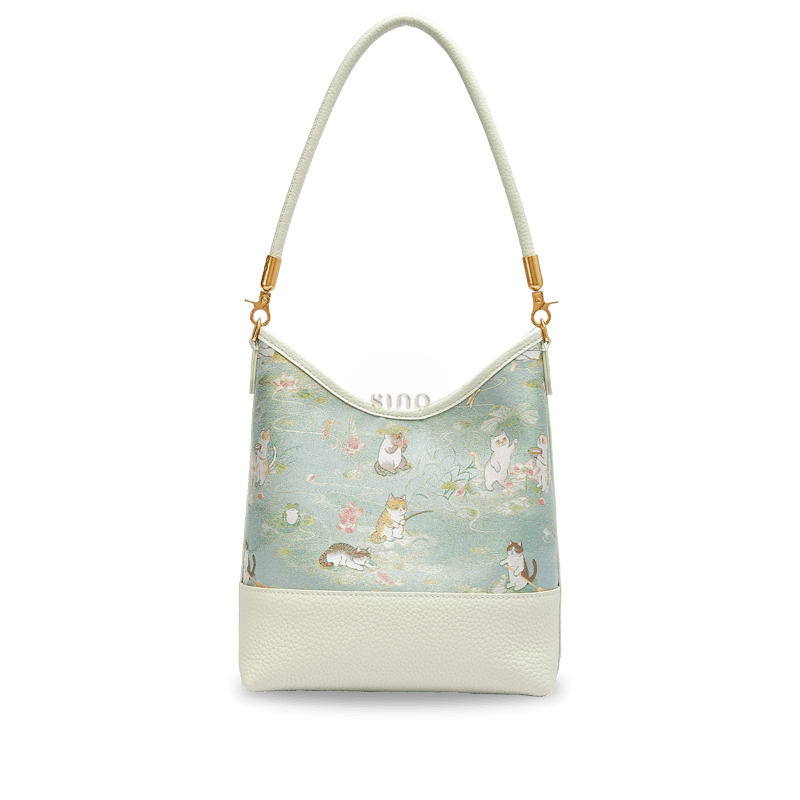 Front view of the Springtime Tales Song Brocade leather shoulder bag featuring playful cats and lotus flowers.