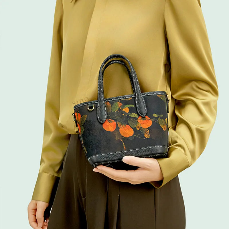 Model standing front-facing holding Chinoiserie Luxury Xiangyunsha Silk Leather Persimmon Handbag.