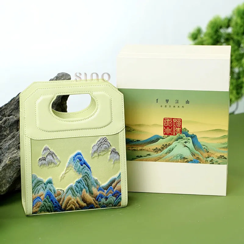 Chinoiserie Mountains Painting hand-embroidered leather handle bag displayed with matching gift box packaging.