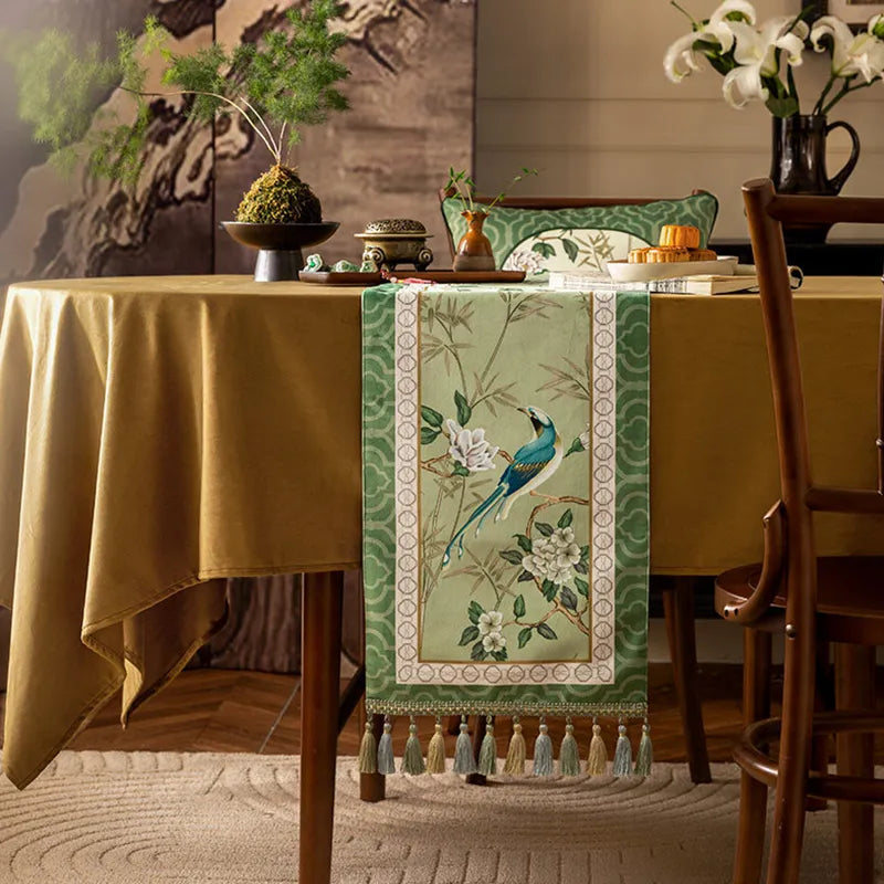 Front view of the jade green chinoiserie long table runner draped over the table edge, highlighting the handmade tassel fringe.