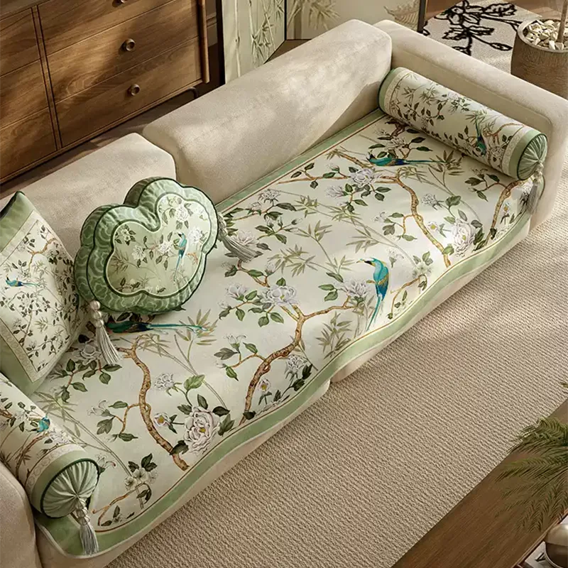 Angled overhead view of jade green chinoiserie sofa slipcover on ivory sofa with matching decorative pillows.
