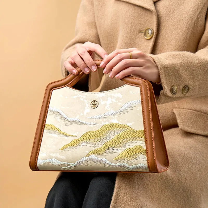 Handmade silk and leather top handle bag featuring Cloud Mountain embroidery, styled as a luxury gift for women.