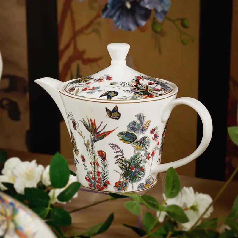 Pear coffeepot displayed with floral wall backdrop.