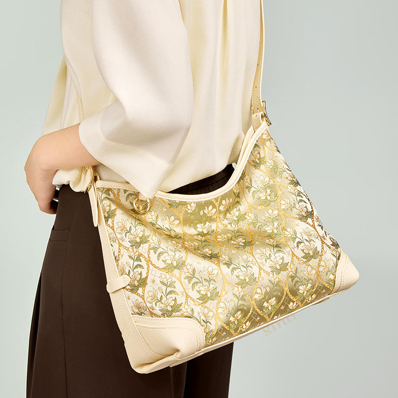 Close-up model view of the Dayun Brocade Verdant Floral Leather Crossbody Bag, highlighting the floral pattern, curved silhouette, and shoulder strap.