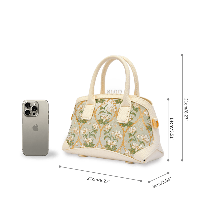 Size and capacity comparison of the Dayun Brocade Verdant Floral leather top handle bag beside a smartphone.