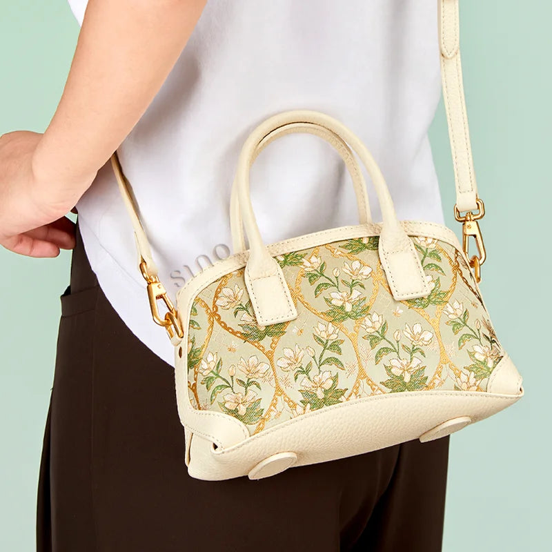 Lifestyle view of the Luxury Verdant Floral leather top handle bag styled with a modern neutral outfit.