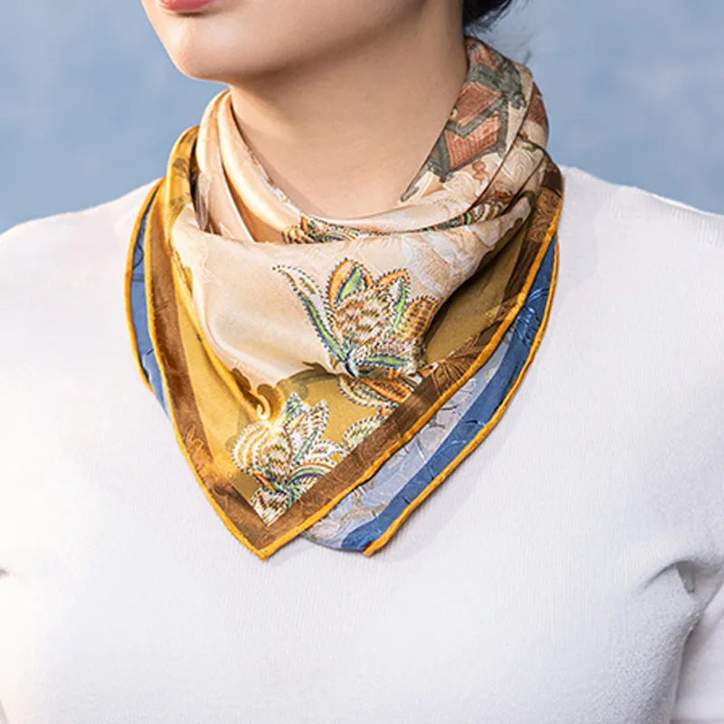 Double-sided Nanjing Brocade Bloom mulberry silk square scarf styled around the neck, showing gold and blue color contrast.
