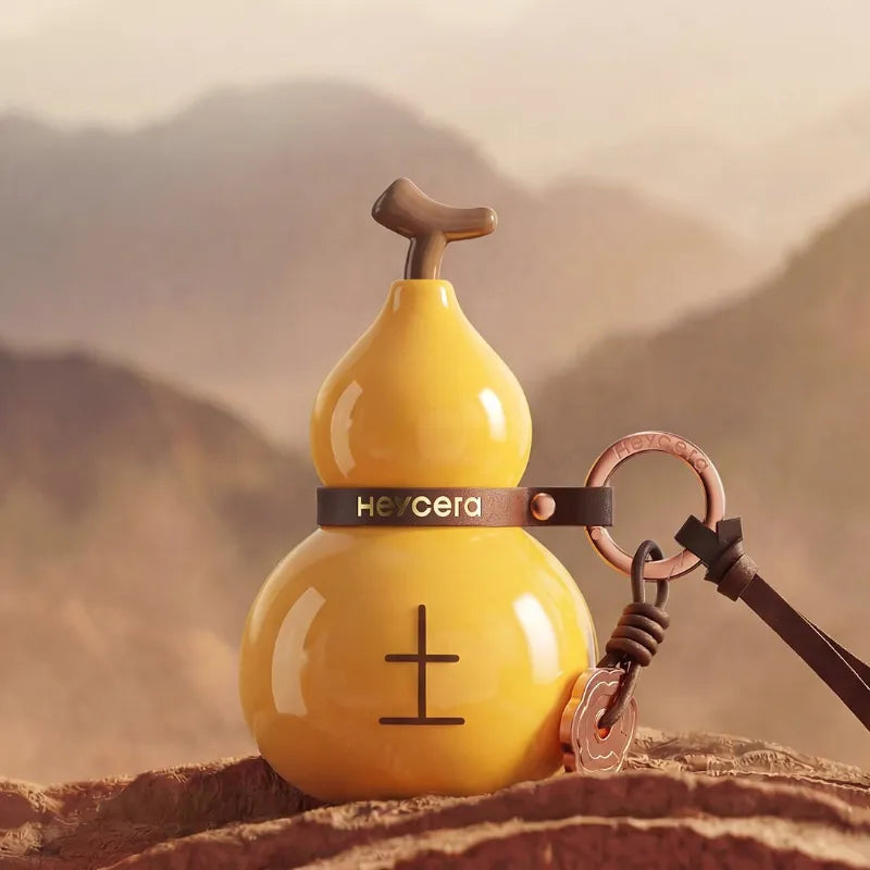 Yellow Earth element porcelain Hulu bag charm displayed against a warm earthy mountain landscape with brown leather details.