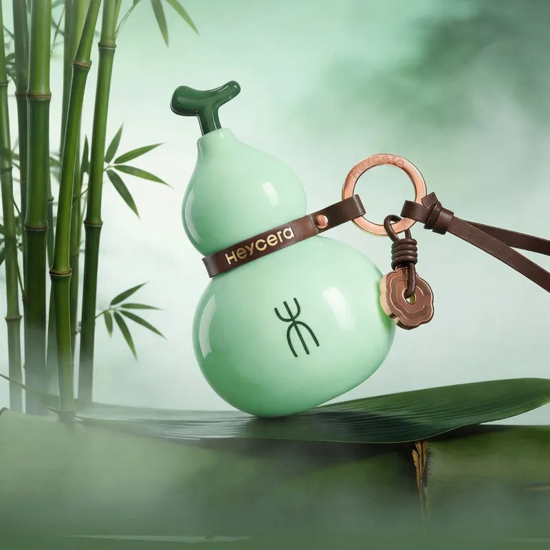 Light green Wood element porcelain Hulu bag charm displayed with bamboo, a brown leather strap, and bronze-tone hardware.