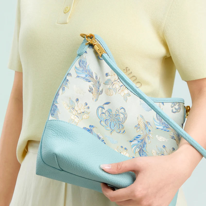Model holding the Golden Jade Romance Shu Brocade leather shoulder bag with a soft pastel outfit.