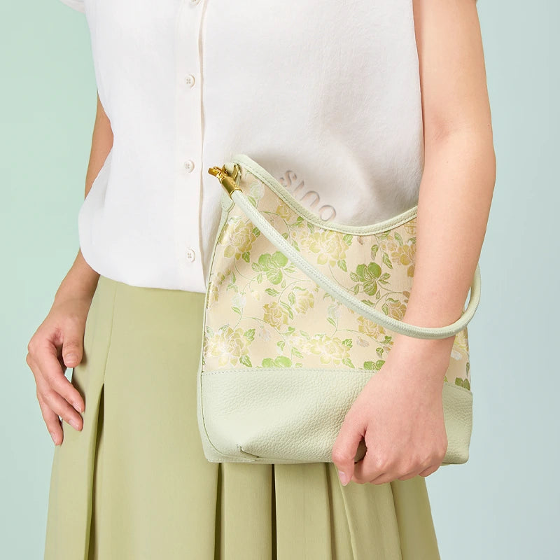 Model holding the Jasmine Green Plum Song Brocade leather shoulder bag with a light neutral outfit.