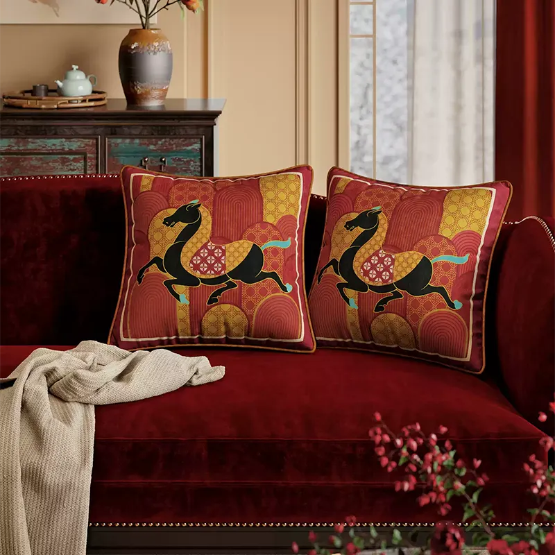 Two red fortune horse throw pillows on modern sofa.