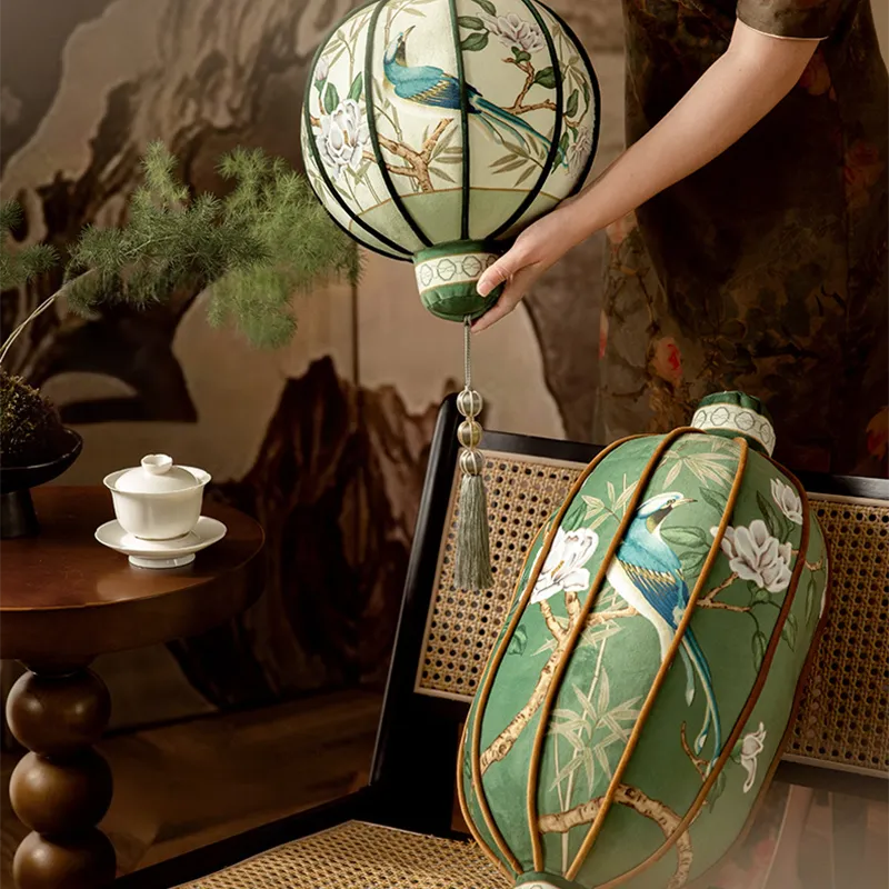 B style lantern-shaped luxury chinoiserie jade green decorative throw pillow on a Chinese-style chair, with a model holding A style lantern pillow.