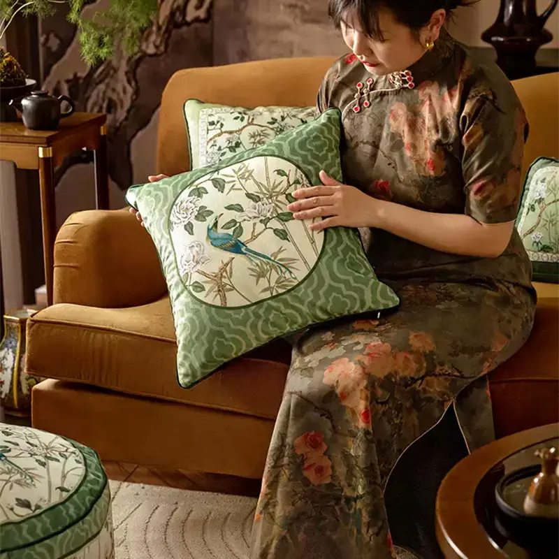 Model holding B style luxury chinoiserie jade green throw pillow on sofa.